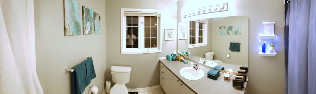 Panorama of bathroom in light grey with green accents.