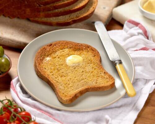 Toast on a plate, butter melting on it, with a butter knife set upon the plate.